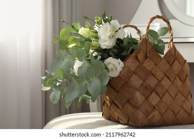 Stylish Wicker Basket With Bouquet Of Flowers On Ottoman In Room