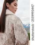 Stylish Winter Elegance - Woman in Luxurious Patterned Coat with Faux Fur Collar in Serene Outdoor Setting.