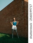 Stylish Woman in Bold Outfit Posing by Brick Wall on a Sunny Day.