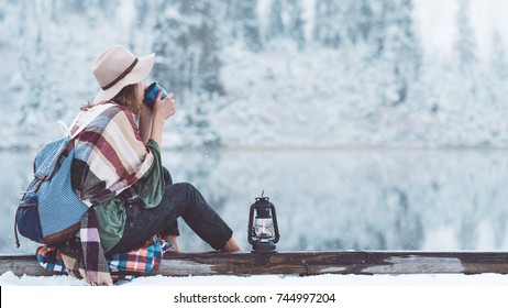 Stylish woman drinking hot coffee and sitting next to stunning winter landscape. Traveling in mountains wilderness. Wanderlust and boho style - Powered by Shutterstock