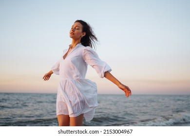Stylish woman in elegant white dress posing near the sea. Summer time. Travel, weekend, relax and lifestyle concept.