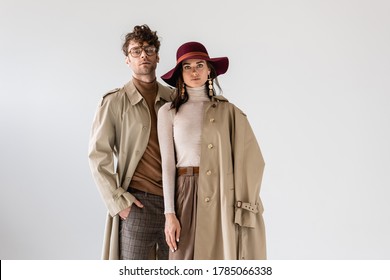 stylish woman in hat and man with hand in pocket posing in autumn clothes isolated on grey - Shutterstock ID 1785066338