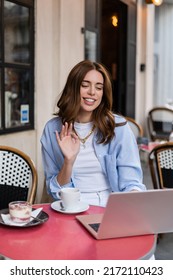 Stylish Woman Having Video Call On Laptop Near Coffee And Desert In Outdoor Cafe In Paris