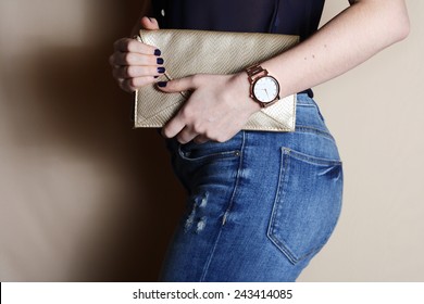 Stylish woman in jeans with small gold clutch and watch . fashion concept. 
