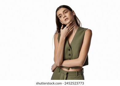 A stylish woman with long dark hair striking a pose in a vibrant emerald green suit against a neutral gray backdrop. Stockfoto