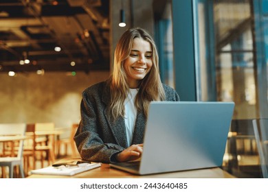 Stylish woman manager freelancer working on laptop while sitting in cozy cafe. High quality photo