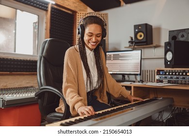 Stylish woman musician, sound composer playing synthesizer and rehearsing new song in the modern recording music studio - Powered by Shutterstock