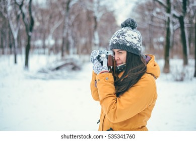 Stylish woman photographer with retro camera in winter park - Powered by Shutterstock