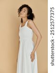 The stylish woman poses gracefully, showcasing her fashionable white dress and radiant confidence.