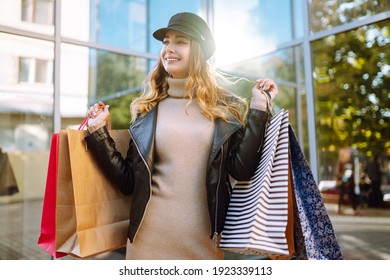 Stylish woman with shopping bags walks through the city streets. Spring Style.  Consumerism, purchases, shopping, lifestyle concept.