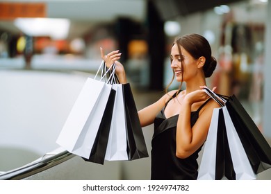 Stylish woman with shopping bags walks in the mall after shopping. Spring Style.  Consumerism, purchases, sales, lifestyle concept.