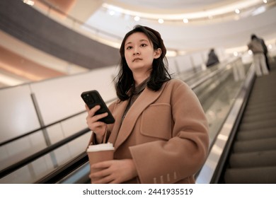 Stylish Woman With Smartphone Riding Escalator in Mall - Powered by Shutterstock