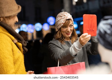 Stylish woman with turban headwrap checking her reflection in handheld mirror while shopping during festive evening season - Powered by Shutterstock