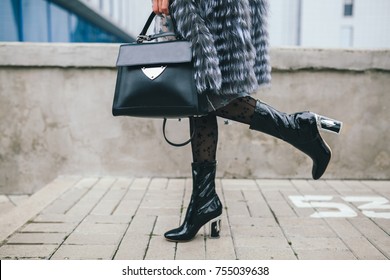 stylish woman walking in city in fur coat, urban street style, winter fashion trend, legs close up, accessories, boots