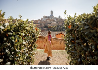 Stylish woman walks on background of cityscape of Siena old town. Concept of travel famous cities in Tosacny region of Italy - Shutterstock ID 2137587261