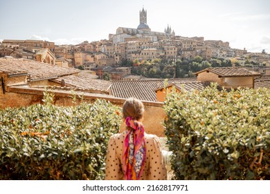 Stylish woman walks on background of cityscape of Siena old town. Concept of travel famous cities in Tosacny region of Italy