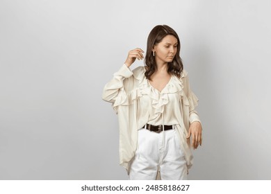 A stylish woman in a white ruffled blouse and white pants stands gracefully. Perfect for fashion and lifestyle themes.
