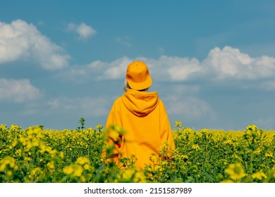 Stylish Woman In Yellow Hoodie And Cap In Rapeseed Field