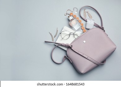 Stylish woman's bag with accessories on light grey background, flat lay. Space for text