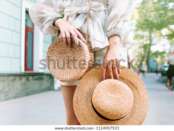 Stylish\
woman\'s outfit. Nature stylish top. Straw bag. White dress.Woman\
hands with fashionable stylish nude rattan bag and straw bag\
outside. Stylish young woman fashion\
details