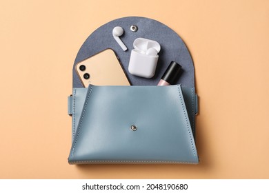 Stylish women's bag and different stuff on pale orange background, top view
