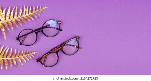 Stylish Women's Glasses On A Purple Background With Golden Palm Leaves, Space For Text. Mockup For Advertising Eyeglasses