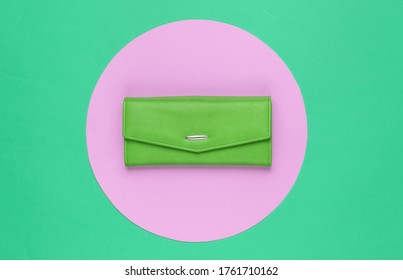 Stylish Women's Green Leather Wallet On Green Background With Pink Pastel Circle. Creative Minimalistic Fashion Still Life. Top View