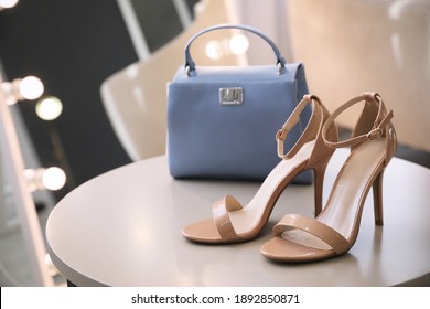 Stylish women's shoes and bag on table in modern boutique