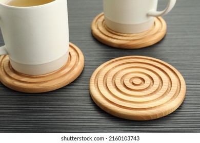 Stylish wooden cup coasters and mugs on black table - Shutterstock ID 2160103743