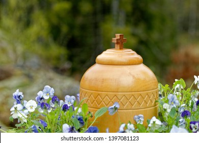 Stylish Wooden Funerary Urn Standing In Nature Among Blue And White Violets Ready For Spreading Of The Ashes