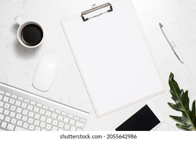 Stylish work table with blank notebook pages, keyboard, glasses, smartphone and coffee mug on marble table