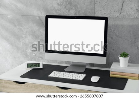 Stylish workplace with computer and black mousepad on white table indoors. Space for text