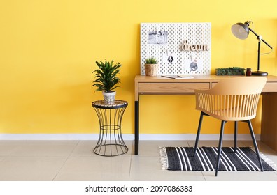 Stylish Workplace With Peg Board On Yellow Wall Background