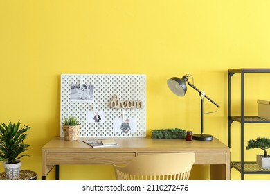 Stylish Workplace With Peg Board On Yellow Wall Background