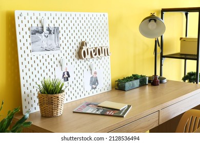 Stylish Workplace With Peg Board On Yellow Wall Background