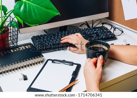 Stylish workspace with computer desktop, keybord, cup of coffee, office supplies, houseplant and clipboard at home or studio. Selective focus. Work from home concept.