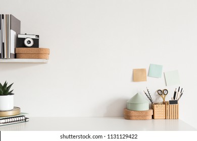 Stylish workspace desk with accessories, houseplant, sticky notes, camera on white wall background. - Powered by Shutterstock