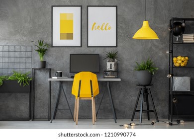 Stylish yellow and grey home office with industrial furniture and urban jungle, real photo with posters on concrete wall - Powered by Shutterstock