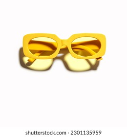 Stylish yellow sunglasses with transparent yellow glass isolated on white background, shadow from sunlight, summer fashion plastic-framed glasses. Summer sale concept. Top view eyeglasses photo