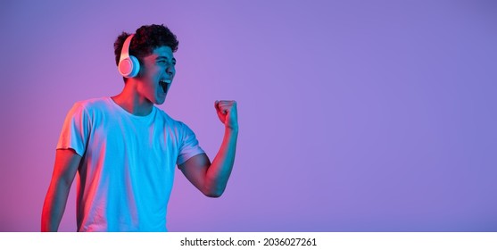 Stylish Young Asian Man Isolated Over Lilac Color Studio Background In Pink Neon Light. Concept Of Human Emotions, Facial Expression, Youth Culture, Diversity. Listening To Music. Flyer