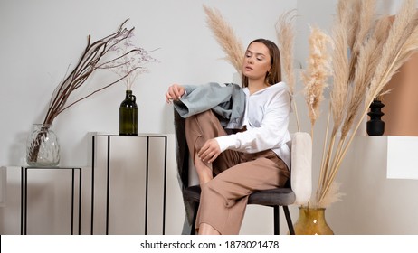 Stylish young brunette in a white shirt, casual style modern look, stylish and minimalistic portrait in the interior, decorative dried flowers pampas grass and branches in a vase - Powered by Shutterstock