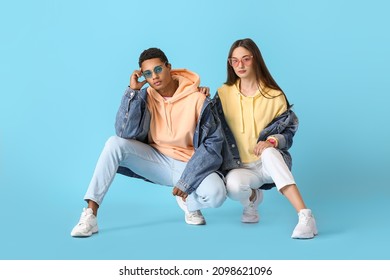 Stylish young couple in hoodies on blue background