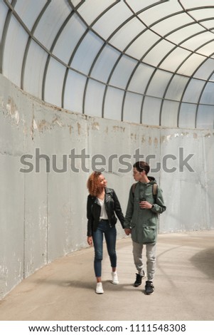 Stylish young couple walking holding hands.
