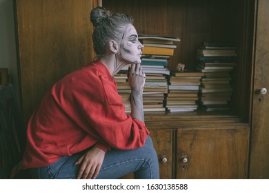 Stylish young  girl and cartoon body art sitting against vintage wooden cupboard and books 