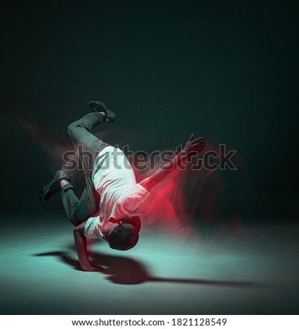 Stylish young guy breakdancer dancing hip-hop in neon light. Dance school poster. Long exposure shot