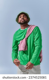 stylish young man in green panama with pink sweatshirt tied on his shoulders, fashion concept