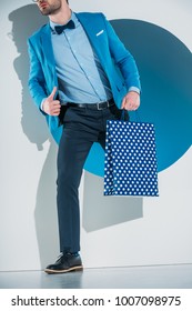 Stylish Young Man With Shopping Bag Stepping Through Hole On Grey