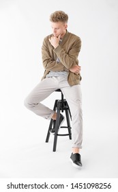 Stylish Young Man Sitting On Stool Against White Background