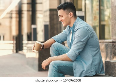 Stylish Young Man Sitting On Stairs Outdoors On The City Street Holding Cup Drinking Hot Coffee Laughing Happy Side View