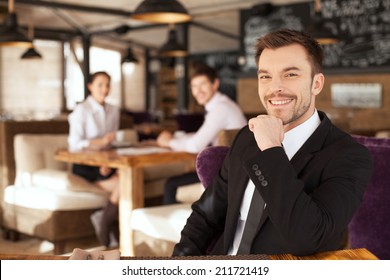 Stylish young man sitting in restaurant. closeup of handsome man drinking glass of red wine and friends on background